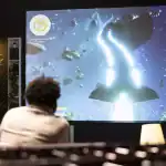 Building an 8K video home theater system(Instruction) 3 Person watching a space-themed 8K video on a large home theater screen.